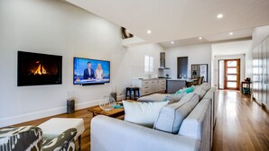 A modern living room with a fireplace, a television, and a sofa. - Majestic on Palm Beach, Jervis Bay (Sanctuary Point)