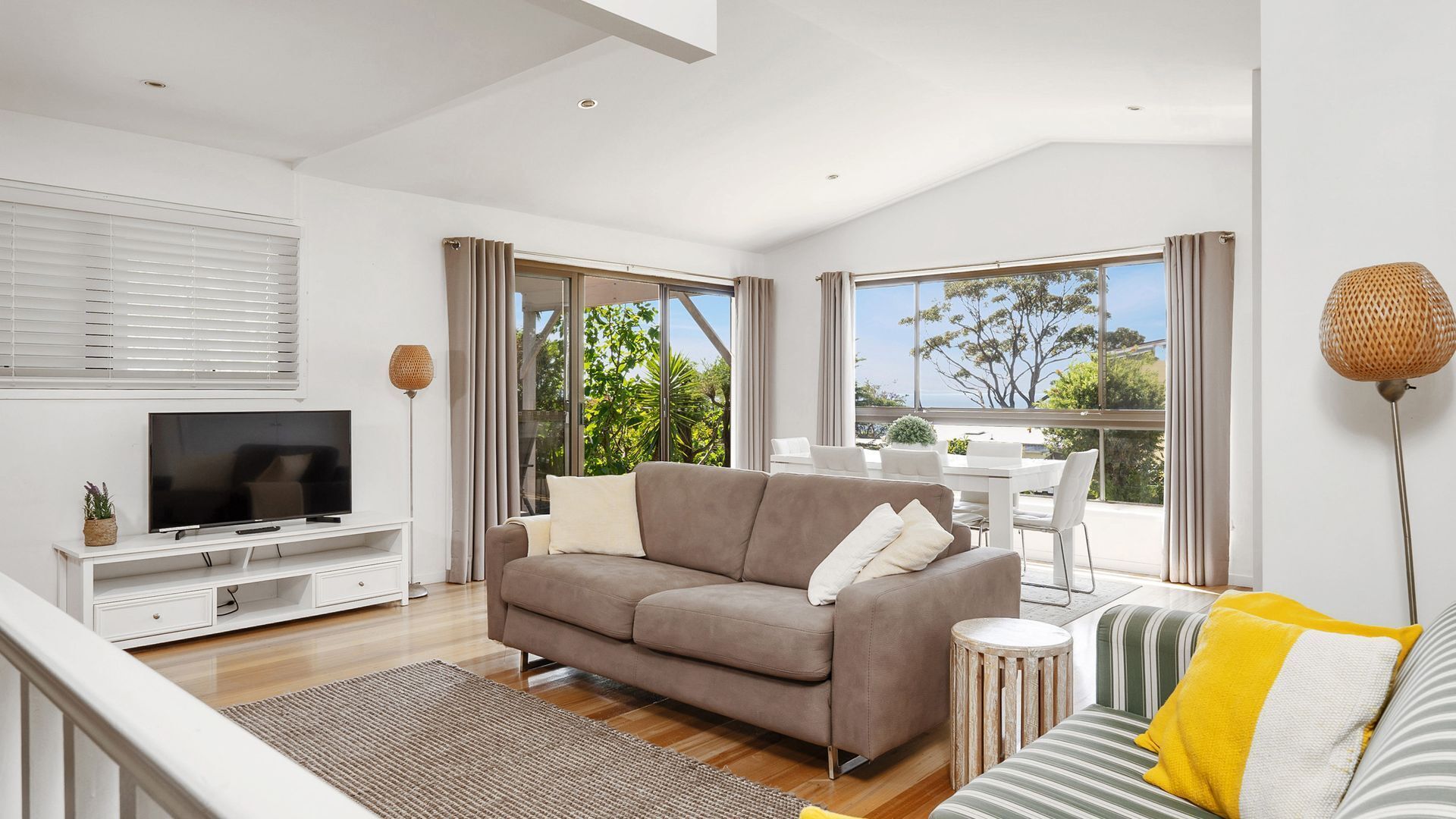 A modern living room with a sofa, TV, and dining area.
