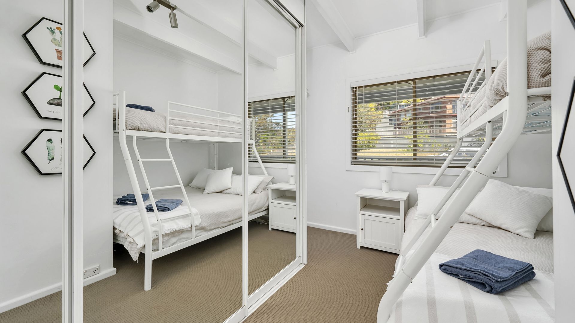 A bunk bed room with a window, a desk, and a chair.