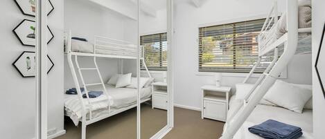A bunk bed room with a window, a desk, and a chair.