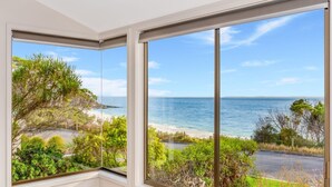 Una habitación con amplios ventanales que dan a una playa y al océano.