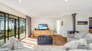 Una sala de estar moderna con televisor, chimenea y un ventanal con vistas a una terraza.