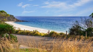 Una carretera costera que lleva a una playa con aguas azules cristalinas y una orilla de arena.