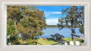 A lakeside property with a deck, a small cabin, and a picnic table.