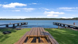 A lakeside picnic area with a wooden bench and a tire.