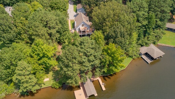 An aerial view of a house surrounded by dense trees, with a dock extending into a body of water. - Beautiful Lake Front in Quiet Cove, Convenient to Boat Ramp, Dining & Shopping (Henrico)