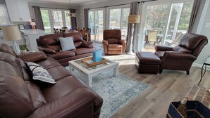 A spacious living room with a brown leather sofa set, a coffee table, and a dining area with a table and chairs. - Beautiful Lake Front in Quiet Cove, Convenient to Boat Ramp, Dining & Shopping (Henrico)