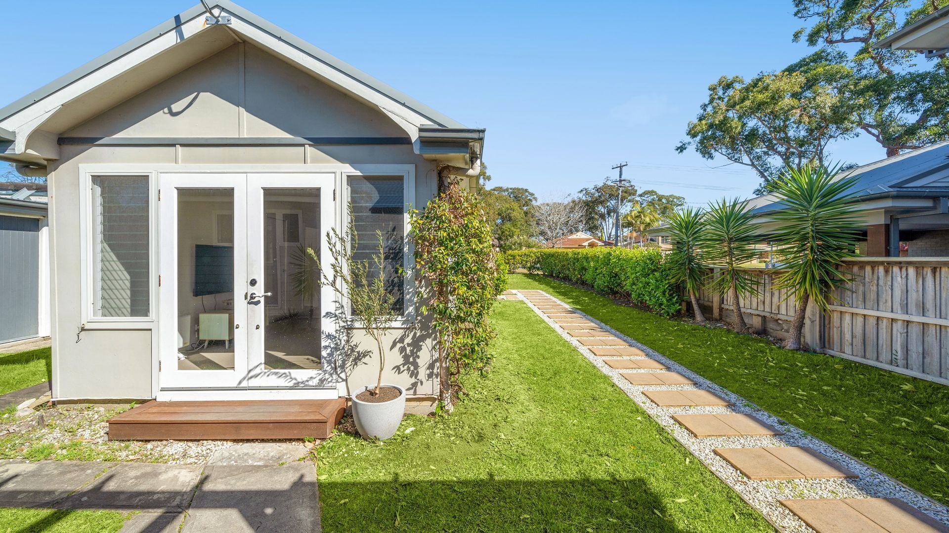 Une maison de plain-pied avec un porche abrité, un petit jardin et un chemin menant à l’entrée.
