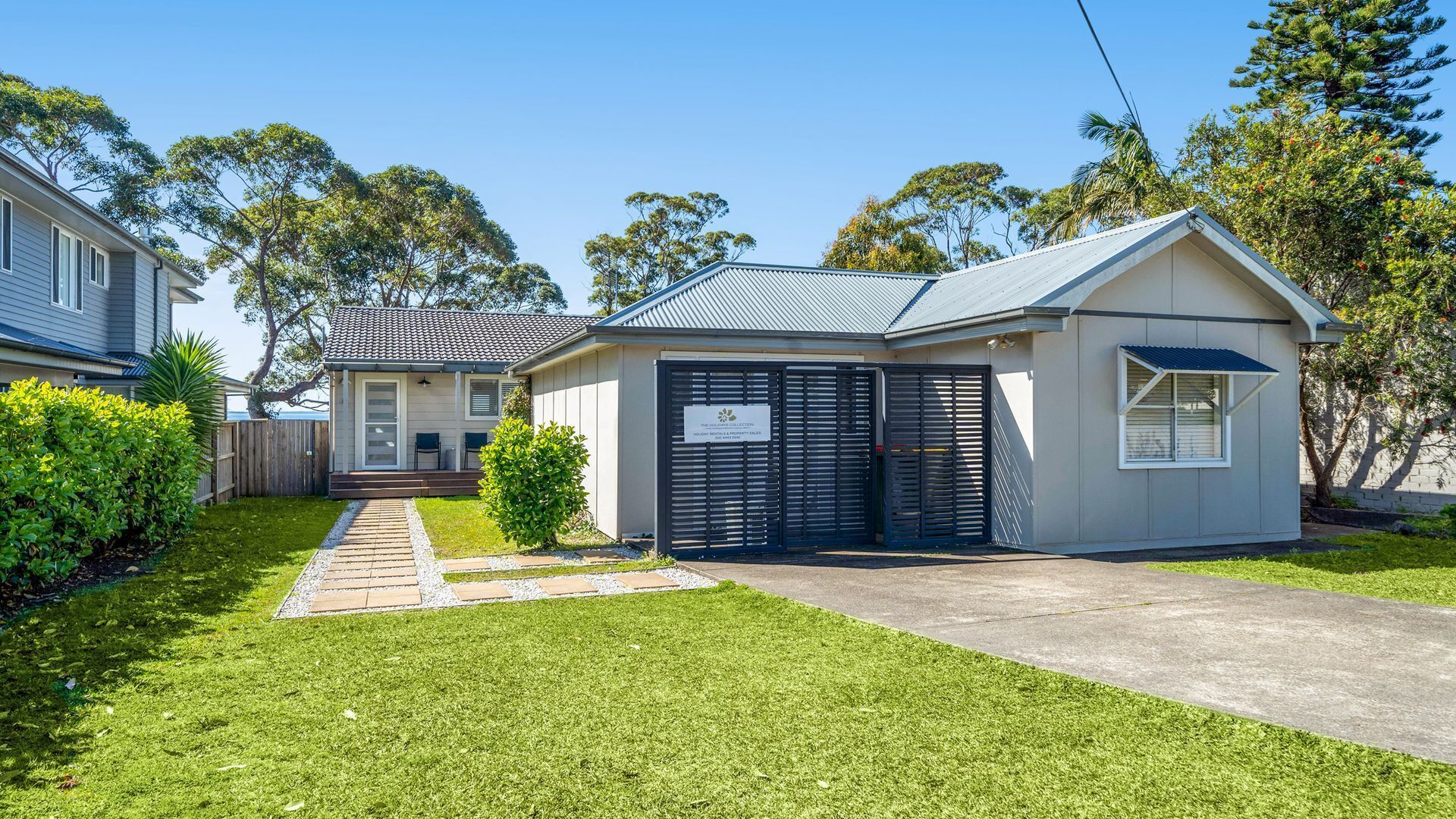 A two-story house with a covered porch, a gated garage, and a well-maintained lawn.