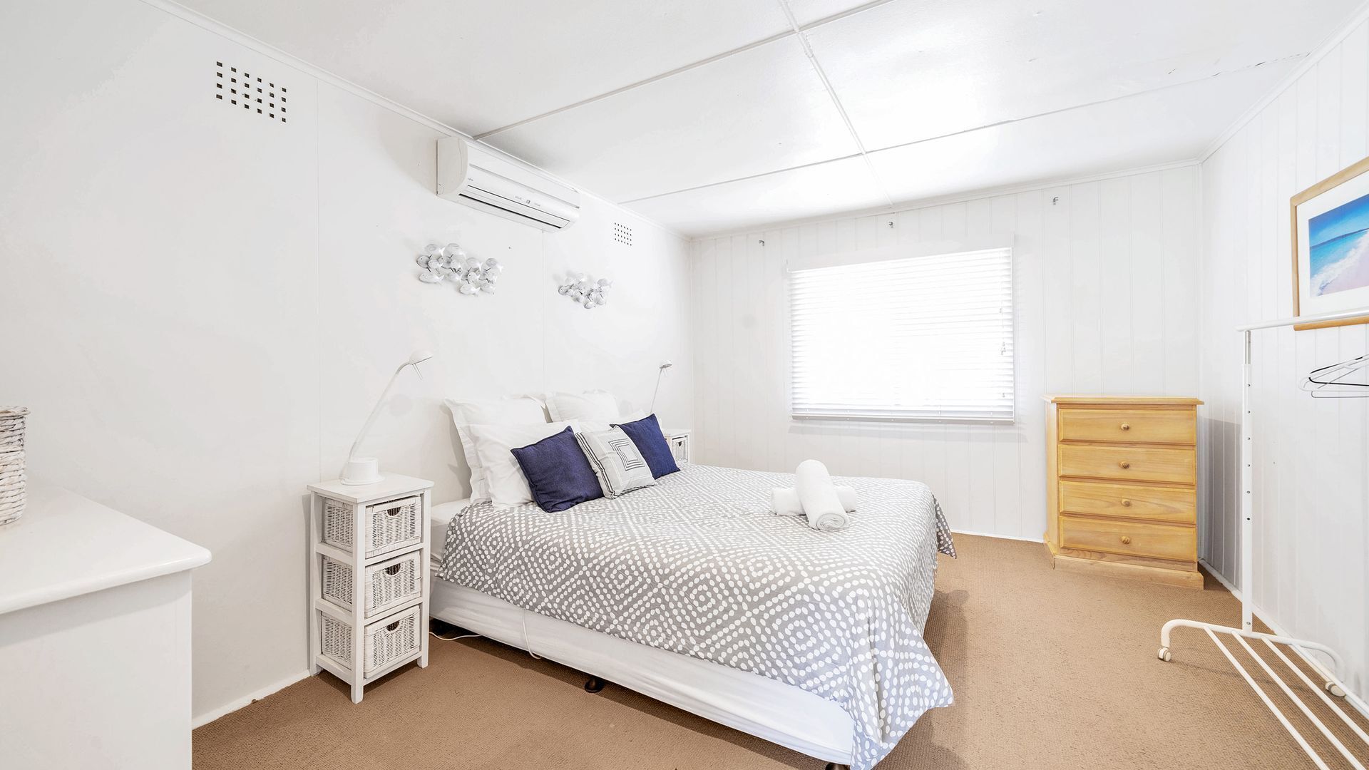 Un dormitorio con cama, mesita de noche, cómoda y ventana.