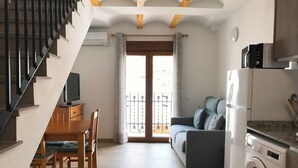 A compact living space with a staircase, a dining area, a sofa, a washing machine, and a balcony. - Alojamiento con terraza en Chulilla (Chulilla)