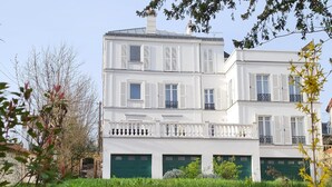 Een wit gebouw met meerdere verdiepingen, balkons en groene garage deuren.