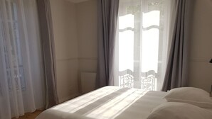 Een slaapkamer met een bed, een raam met gordijnen en een radiator.