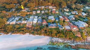 An aerial view of a coastal residential area with houses, roads, and a beach. - Sandals at the Bay - Downstairs, Hyams Beach (Hyams Beach)