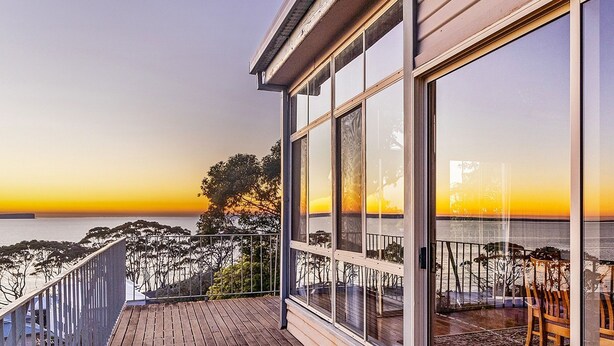 A balcony with a view of the sea and trees at sunset. - Sea Point at Hyams Beach (Hyams Beach)