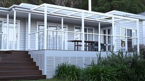 Uma casa moderna com varanda coberta, escadaria de madeira e área de jardim.
