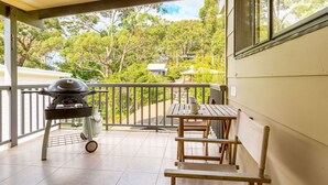 A balcony with a grill, a table, and chairs. - Shanti at Hyams Beach, Jervis Bay (Hyams Beach)