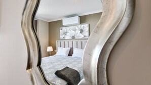 Um quarto com uma cama, uma mesa de cabeceira, uma luminária e uma grande obra de arte floral na parede.