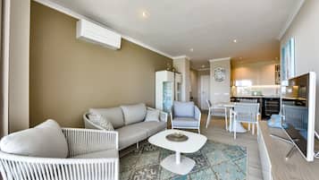 Una sala de estar moderna con un sofá, sillones, una mesa de centro y una zona de cocina con una mesa de comedor y sillas.