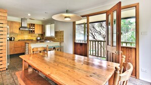 Una cocina moderna con armarios de madera, una isla grande y un comedor con mesa y sillas de madera.