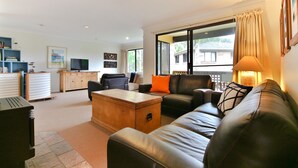 Una sala de estar con sofá, mesa de centro, televisor y estantería.
