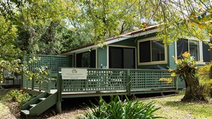 A green wooden building with a sign for 'The Holidays Collection' offering holiday rentals and property sales.