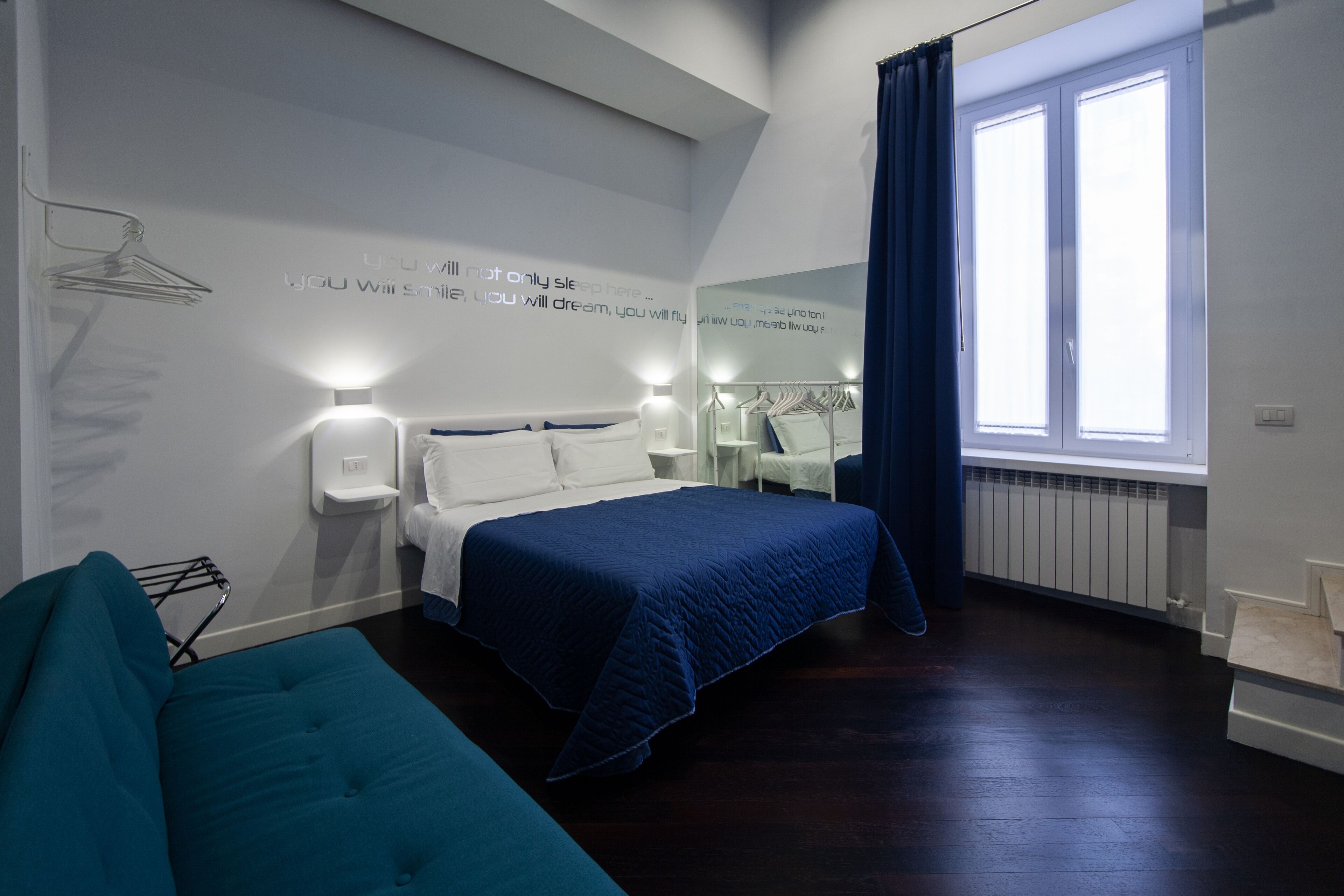 Ein modernes Hotelzimmer mit Bett, einer Sitzecke und einem großen Fenster mit Vorhängen.