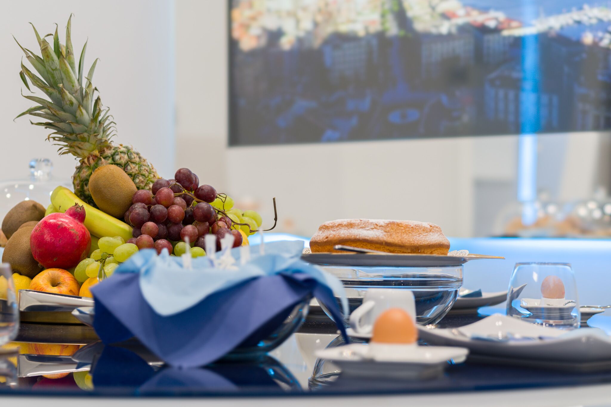Une table dressée pour le petit-déjeuner, avec des fruits, une pâtisserie et un verre d’eau.