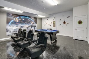 A room with a pool table, gaming chairs, a large space-themed mural, and a door with a circular sticker. - Extremely Private 6-bed House in Four Corners (Davenport)