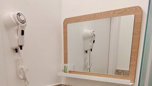 Ein Badezimmer mit einem weißen Waschbecken, einem Spiegel mit Holzrahmen und einem an der Wand befestigten Föhn.