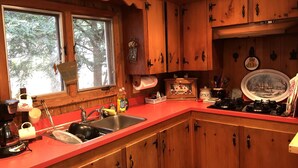 Cucina con mobili in legno, un piano di lavoro rosso, un lavello e una finestra vista alberi.