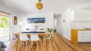 A modern kitchen with white cabinets, a wooden countertop, and a dining area with a wooden table and chairs.