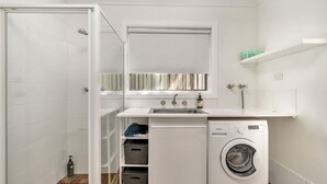 A compact laundry room with a washing machine, a sink, and a mirror above it.