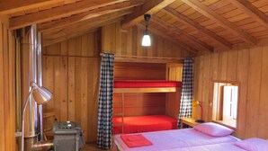 A wooden cabin with bunk beds, a stove, and a window with curtains. - Room in Cabin - Restored, Rustic and Rural Mini Cottage in Typical Portuguese Village (Lamego)