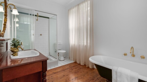 A bathroom with a wooden vanity, a freestanding bathtub, a glass shower enclosure, and a toilet.