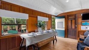 A dining area with a long table set for six, a wooden bench, and a view of the outdoors.