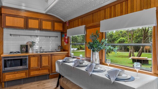 A kitchen with wooden cabinets, a microwave, and a dining area set with plates and glasses.