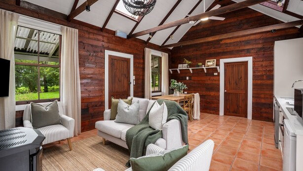 A cozy room with a wooden interior, a sofa, a dining table, and a TV.