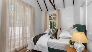 A bedroom with a bed, a nightstand, a lamp, and a window with curtains.