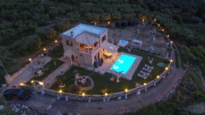 A two-story stone house with a swimming pool, surrounded by a well-lit garden and a circular driveway. - Traditional Fully Private Villa with Pool (Chania)