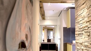 Un pasillo moderno con suelo de madera, una pared de acento de piedra y un cuadro abstracto grande.