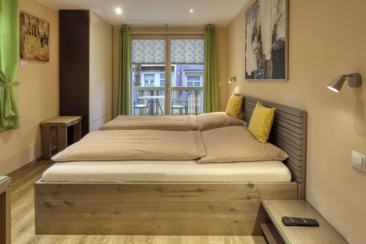 Una cama doble con cabecera de madera, una mesita de noche y una pequeña mesilla.