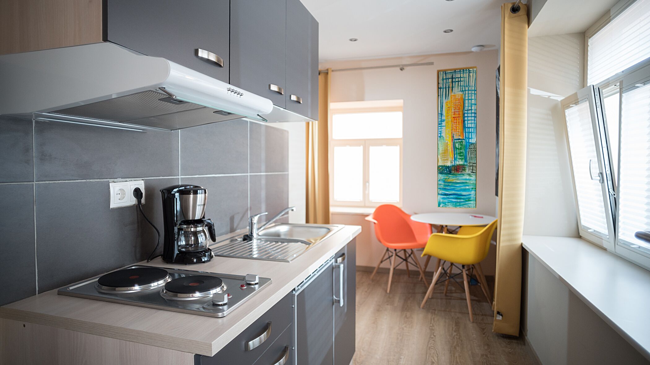 A compact kitchen with a coffee maker, a sink, and a dining area with a table and chairs.