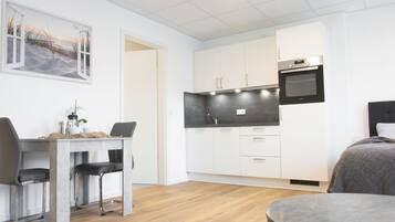 Quarto moderno e compacto com área de refeições, cozinha compacta e uma cama.