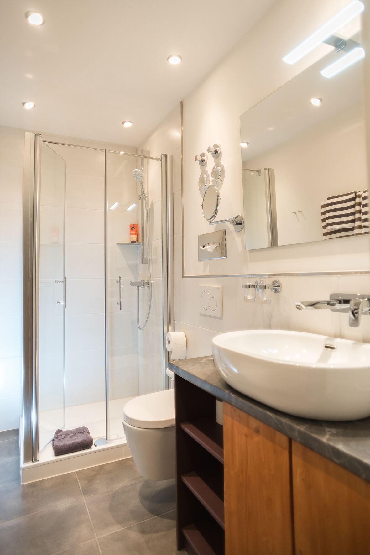 A modern bathroom with a glass shower enclosure, a white sink, and a large mirror.