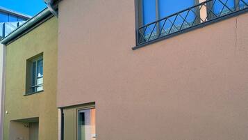 Ein Gebäude mit einer beigefarbenen Fassade, einem Fenster mit Metallgitter und einem Blumentopf im Erdgeschoss.
