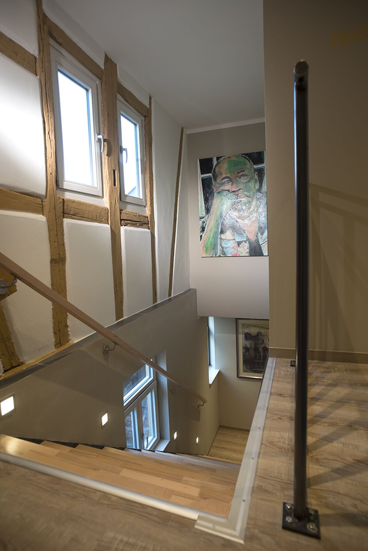 Un escalier avec des marches en bois, une main courante en métal et une balustrade en verre.