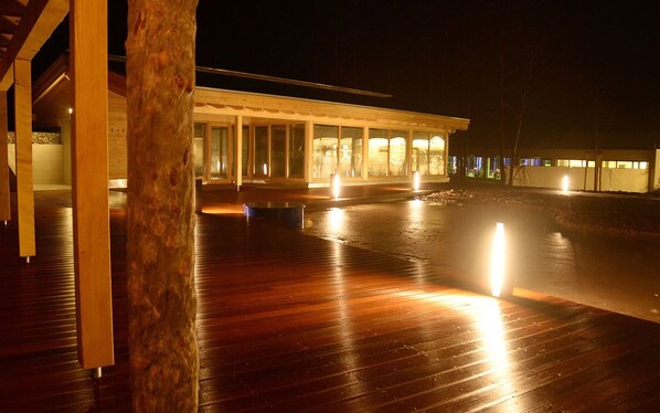 Un edificio moderno con terraza de madera y ventanas amplias.