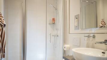 A modern bathroom with a glass-enclosed shower, a white sink, and a toilet.