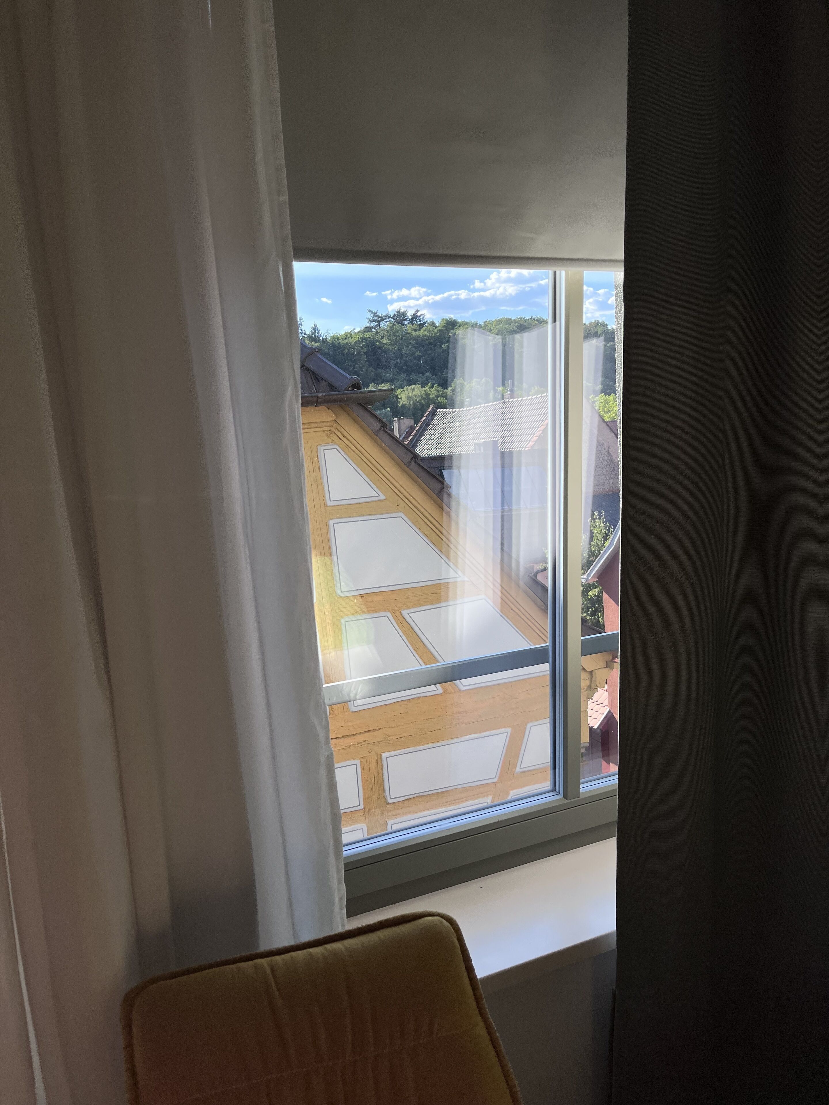 Una stanza con un'ampia finestra che si affaccia su un edificio tradizionale con tetto in tegole.